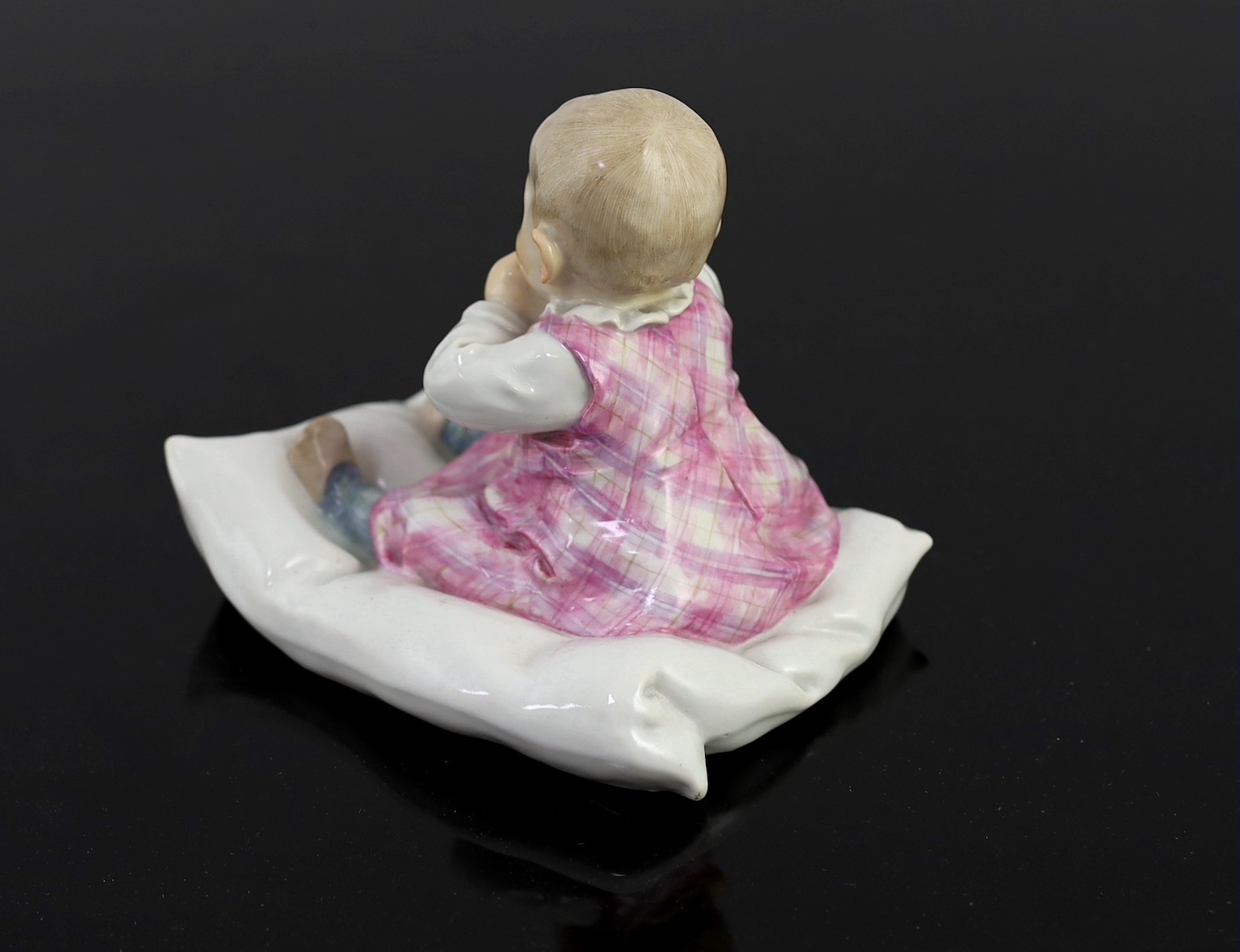 A rare Meissen porcelain figure of a child on a pillow, designed by Conrad Hentschel, c.1905, 12.5cm high